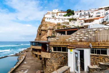 Sintra, Portekiz - 31 Ekim 2022: Azenhas do Mar, Portekiz 'in büyüleyici uçurum manzarası ve kırmızı çatıları olan beyaz boyalı evleri ile tanınan büyüleyici bir kıyı köyüdür..