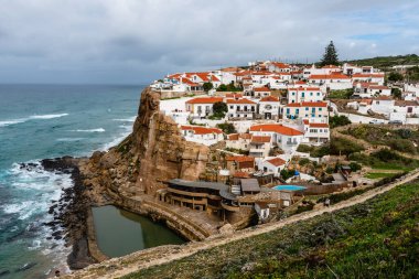 Sintra, Portekiz - 31 Ekim 2022: Azenhas do Mar, Portekiz 'in büyüleyici uçurum manzarası ve kırmızı çatıları olan beyaz boyalı evleri ile tanınan büyüleyici bir kıyı köyüdür..