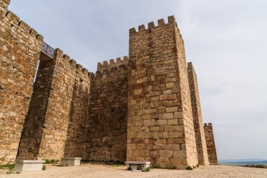 Trujillo, Extremadura, İspanya 'daki ortaçağ şatosunun etkileyici taş duvarlarını ve kulelerini gösteren alçak açılı bir görüntüsü..