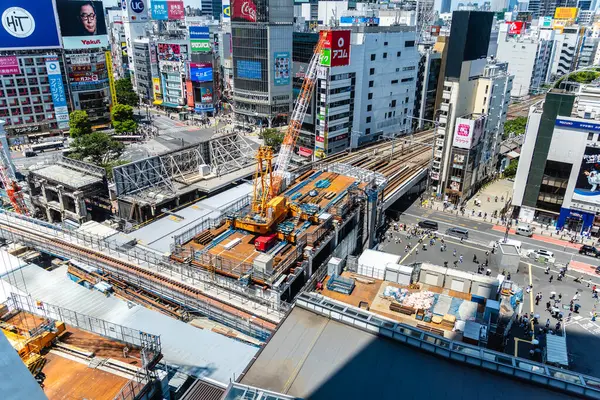 Tokyo, Japonya - 4 Ağustos 2024: Shibuya, Tokyo 'nun etkin inşaatı tren raylarının yanında ve yayaların hareketli faaliyetlerini gösteren manzarası.