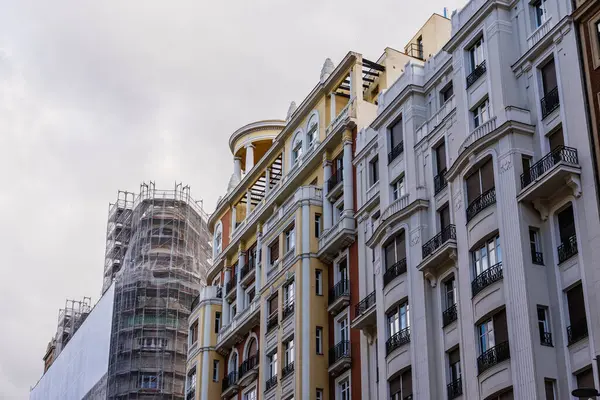 Gran Via caddesindeki Madrid Skyline 'ın görüntüsünde bulutlu bir gökyüzüne karşı dekoratif mimari detaylarla donatılmış bina cepheleri görülüyor..
