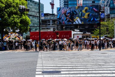 Tokyo, Japonya - 4 Ağustos 2024: Tokyo 'daki ünlü Shibuya geçidini geçmek için bir kalabalık bekliyor..