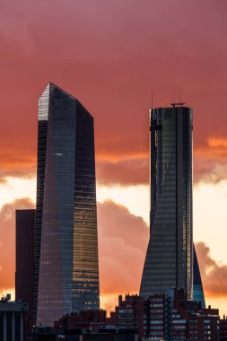 Madrid, İspanya - 8 Aralık 2024: Madrid 'deki Cuatro Torres Business Area gökdelenlerinin çarpıcı görüntüsü günbatımı gökyüzü karşısında modern mimariyi gözler önüne seriyor.