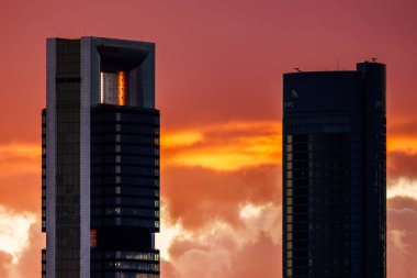 Madrid, İspanya - 8 Aralık 2024: Şehrin iş dünyasının modern mimarisini gözler önüne seren çarpıcı bir günbatımı Madrid, İspanya 'nın ufuk çizgisini aydınlatıyor.
