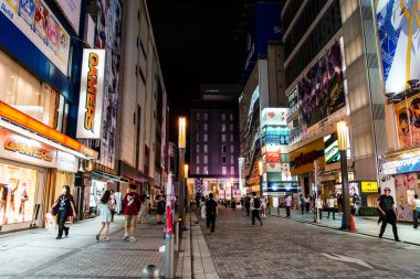 Tokyo, Japonya - 6 Ağustos 2024: Canlı bir sokak sahnesi, geceleri yayalar ve renkli mağazalarla Akihabaras otaku kültürünün özünü yakalar.