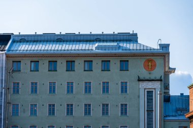 Helsinki, Finlandiya - 19 Ağustos 2024: Ön cephede bir amblem ve düzenli bir düzende sayısız pencerenin yer aldığı bir Helsinki binasının ayrıntıları.