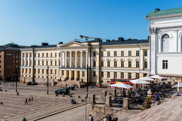 Helsinki, Finlandiya - 19 Ağustos 2024: Güneşli bir gün Helsinki 'nin mimarisini, açık hava kafelerin keyfini çıkaran ve meydandan geçen insanları gösteriyor.