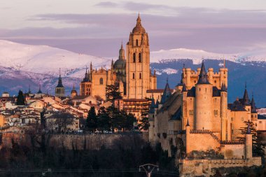 İspanya 'daki karlı Guadarrama dağlarına karşı Segovia ikonik Alcazar ve Katedral' in panoramik manzarası. Gün batımında görüntüle