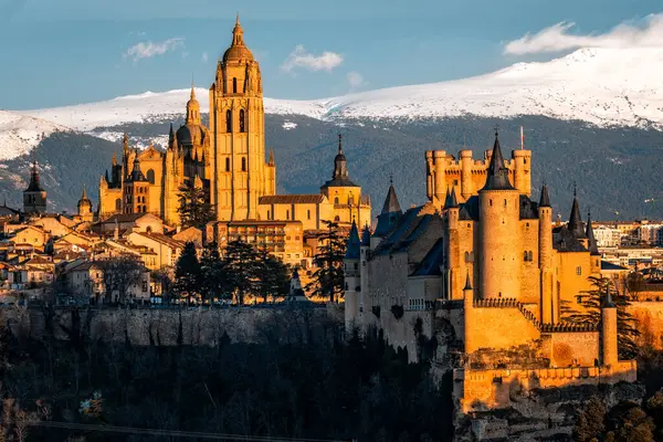 İspanya 'daki karlı Guadarrama dağlarına karşı Segovia ikonik Alcazar ve Katedral' in panoramik manzarası. Gün batımında görüntüle