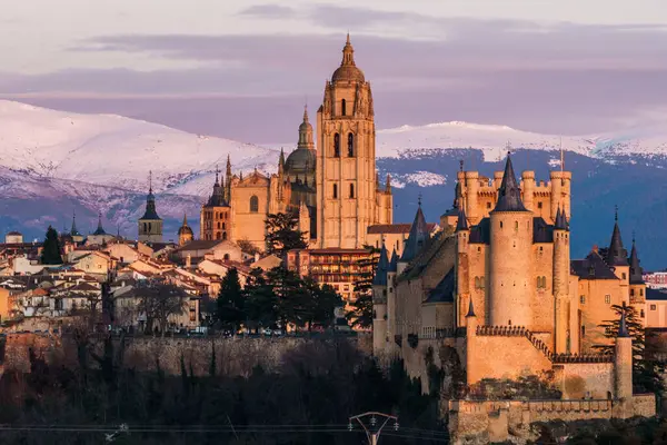 İspanya 'daki karlı Guadarrama dağlarına karşı Segovia ikonik Alcazar ve Katedral' in panoramik manzarası. Gün batımında görüntüle