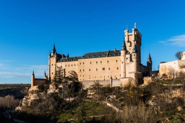 Açık mavi gökyüzünün altındaki Segovia Alcazar 'ın panoramik görüntüsü.