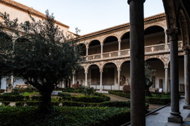 Toledo, İspanya - 23 Aralık 2024: Santa Cruz Hastanesi Manastırı. Alonso de Covarrubias tarafından tasarlandı. Eski sütunları ve taş işçiliğiyle huzurlu bir bahçe..