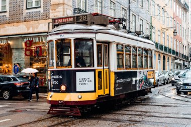 Lisbon, Portugal - October 29, 2022: A classic yellow tram travels through the historic Alfama district of Lisbon, Portugal.
