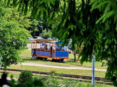 Tren vagonu rayların üzerinde duruyor, yanında bir bisiklet ve insanlar içeri giriyor.