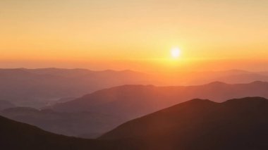 Gün batımında eşsiz dağ manzarasının panoramik manzarası ve ön planda büyük kayalar.