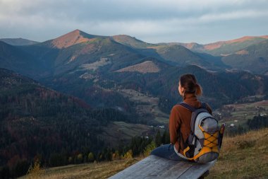 Happy woman with a backpack enjoying nature in the mountains and looking at the morning landscape. Freedom concept