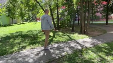 Bir insan, verimli ve canlı yeşil bir parkta kendi yolunu çizen bir yolda rahatça yürüyor.