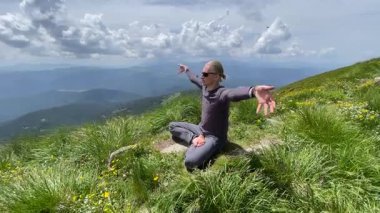 Nilüfer pozisyonunda genç bir adam güzel bir dağda meditasyon yapıyor. Etrafı doğanın huzuruyla çevrili.
