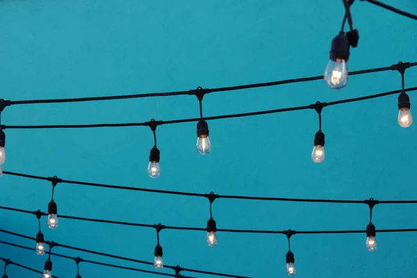 Light bulbs hanging on a wire in front of a blue wall