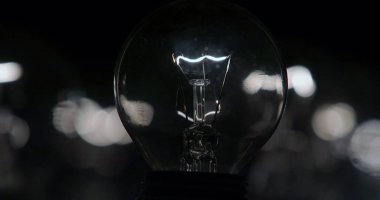 Bokeh arkaplanlı karanlıkta ampul, enerji kavramı