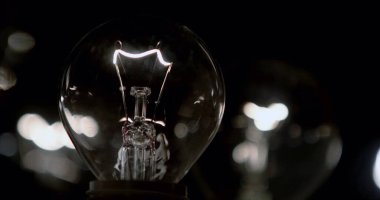 Bokeh arkaplanlı karanlıkta ampul, enerji kavramı