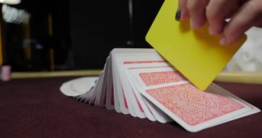 Kırmızı masada elinde fiş ve kartlarla poker oynayan kadın. Eline odaklan.