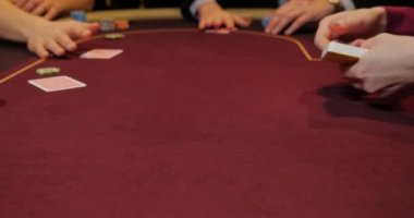 Kırmızı masada elinde fiş ve kartlarla poker oynayan kadın. Eline odaklan.
