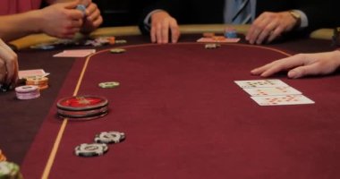 Kırmızı masada elinde fiş ve kartlarla poker oynayan kadın. Eline odaklan.