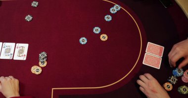 Kumarhanede poker oynayan krupiye. Eller ve cipsler masaya yakın olsun.