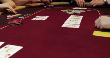 Kumarhanedeki kırmızı masada poker fişleri ve kartlar.