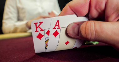 Kumarhanede kağıt oynamak. Kartı tutan bir kadının yakın çekimi.