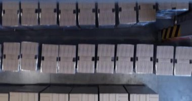 Depodaki kutuları beyaz arkaplana karşı taşıyan forkliftlerin yüksek açılı görünümü