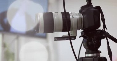 Arka planda bulanık bir kadın arkaplanı olan bir tripoda kamera.