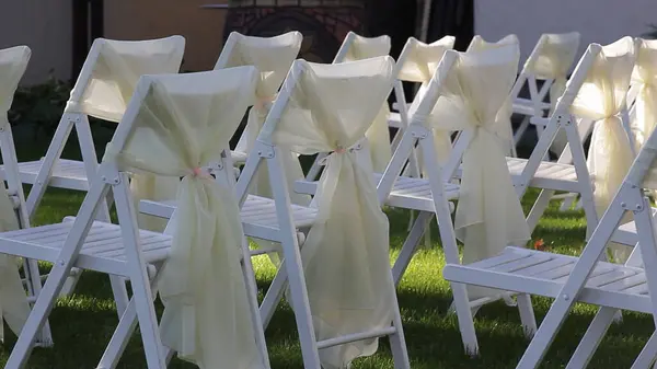 wedding chairs on a green lawn in the shade of trees