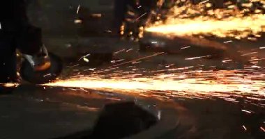 Erkek el nargile parçaları açısı öğütücü ile keser. Bir çelik inşaat alanında kıvılcım sıçraması ile kesme. Metal açılı taşlama kesim sırasında kıvılcım