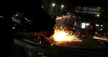 Erkek el nargile parçaları açısı öğütücü ile keser. Bir çelik inşaat alanında kıvılcım sıçraması ile kesme. Metal açılı taşlama kesim sırasında kıvılcım