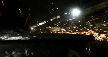 Erkek el nargile parçaları açısı öğütücü ile keser. Bir çelik inşaat alanında kıvılcım sıçraması ile kesme. Metal açılı taşlama kesim sırasında kıvılcım