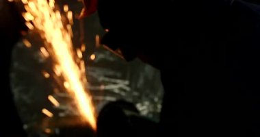 Erkek el nargile parçaları açısı öğütücü ile keser. Bir çelik inşaat alanında kıvılcım sıçraması ile kesme. Metal açılı taşlama kesim sırasında kıvılcım