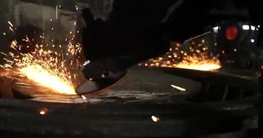 Erkek el nargile parçaları açısı öğütücü ile keser. Bir çelik inşaat alanında kıvılcım sıçraması ile kesme. Metal açılı taşlama kesim sırasında kıvılcım