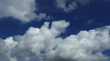 Zaman hızlandırılmış bulutlar mavi gökyüzüne karşı gökyüzünde yüzerler.