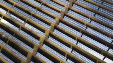 Temiz elektrik üretmek için birçok sıra güneş fotovoltaik paneli olan büyük bir enerji santralinin havadan görünüşü. Sıfır emisyonlu yenilenebilir elektrik