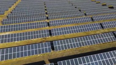 Temiz elektrik üretmek için birçok sıra güneş fotovoltaik paneli olan büyük bir enerji santralinin havadan görünüşü. Sıfır emisyonlu yenilenebilir elektrik