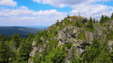 Yükselen kaya oluşumları, Almanya 'daki Sakson İsviçre Dağları' nda açık bir gökyüzünün altında yemyeşil bir ormanın ortasında duruyor..