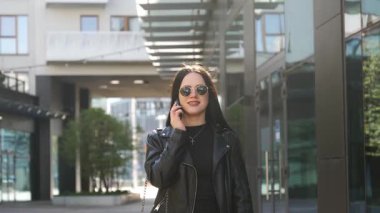 Kız telefonda yürüyor ve konuşuyor. Modern şehir işleri.