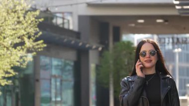 Kız telefonda yürüyor ve konuşuyor. Modern şehir işleri.