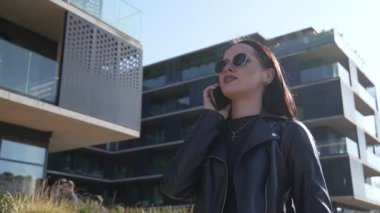 Kız telefonda yürüyor ve konuşuyor. Modern şehir işleri.