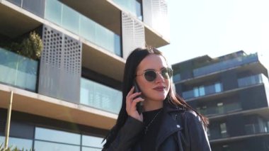 Kız telefonda yürüyor ve konuşuyor. Modern şehir işleri.