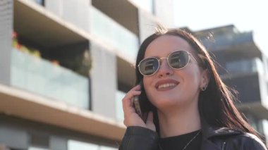 Kız telefonda yürüyor ve konuşuyor. Modern şehir işleri.