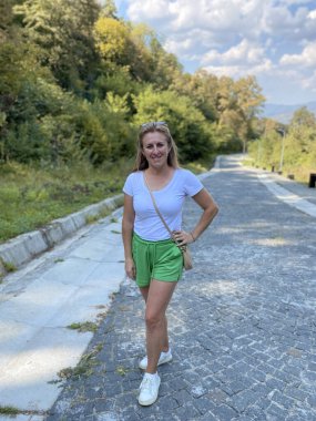 Yeşil çimenler, ağaçlar, yürüyüş yolları ve dışarıda yürüyen insanlarla dolu sessiz bir park..