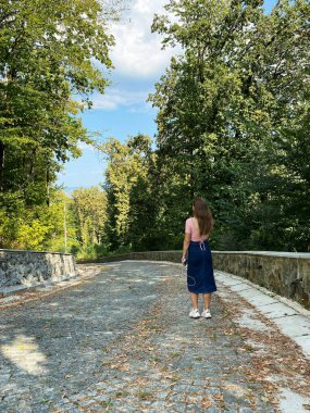 Yeşil çimenler, ağaçlar, yürüyüş yolları ve dışarıda yürüyen insanlarla dolu sessiz bir park..